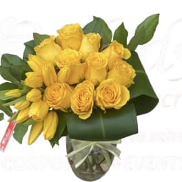 Yellow roses and lilies arranged in a glass vase