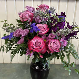 Pink roses and purple flowers arranged in a black vase