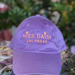 Purple baseball cap with orange embroidered text reading "Miss Daisy Las Vegas"