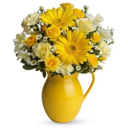 Yellow and white flower bouquet in a yellow pitcher vase