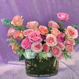 Pink and peach roses arranged in a clear glass vase