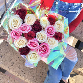 Bouquet of pink, white, and burgundy roses wrapped in iridescent paper