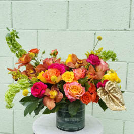 Bright mixed bouquet in a dark vase with orange, pink, and yellow blooms