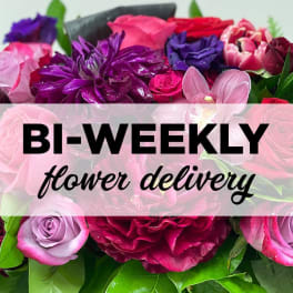 Mixed bouquet of pink, purple, and red flowers with a delivery banner