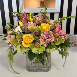 Mixed bouquet of yellow roses and pink flowers in a clear glass vase