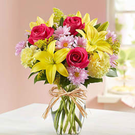 Bouquet of pink roses and yellow lilies in a glass vase