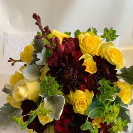 Bouquet of yellow roses and dark burgundy dahlias with silvery foliage