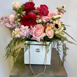 Mixed pink and red roses arranged in a white box with trailing greenery