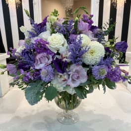 Purple and white floral arrangement in a clear glass vase