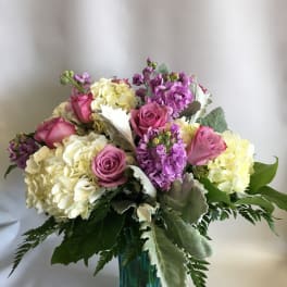 Pink roses and pale hydrangeas arranged in a blue glass vase