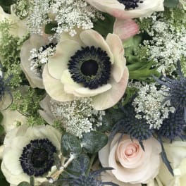 Bouquet of white anemones, pale roses, and blue thistles
