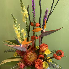 Tropical floral arrangement with orange roses and bird-of-paradise blooms