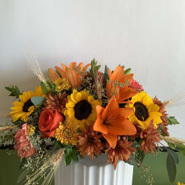 Bouquet of sunflowers, orange lilies, and roses in a white vase