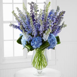 Blue and purple flowers arranged in a clear glass vase