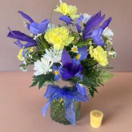 Blue and yellow bouquet in a glass vase with a ribbon