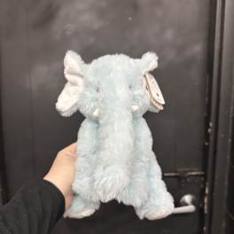 Light blue plush elephant toy being held in front of a dark door