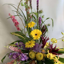 Tall mixed bouquet with yellow gerberas, purple blooms, and pink flowers