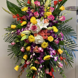 Large standing floral spray with roses, lilies, orchids, and yellow blooms