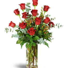 Tall arrangement of red roses in a clear glass vase with stones at the bottom
