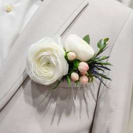 White floral boutonniere with small pink berries on a light beige suit lapel
