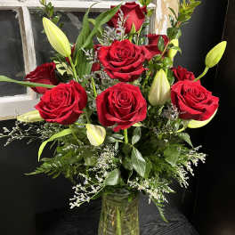 Red roses and lily buds in a clear glass vase