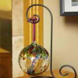 Decorative metal stand holding a colorful glass orb