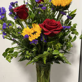 Bouquet of red roses and yellow sunflowers in a clear glass vase