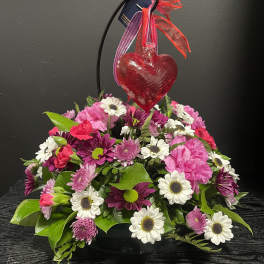 Pink and white flower arrangement with a red heart ornament