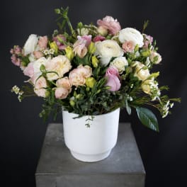 Pastel bouquet of roses and ranunculus in a white vase