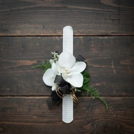 White orchid wrist corsage with black ribbon on a white band