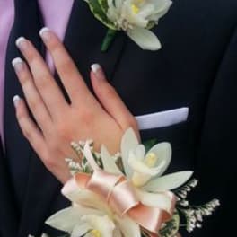 White corsage and boutonniere with ribbon on a dark suit