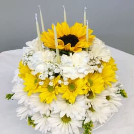 Tiered yellow and white flower cake with candles