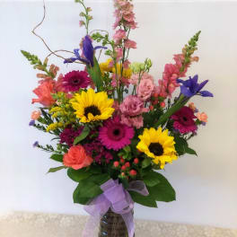 Colorful mixed bouquet in a glass vase with a purple ribbon