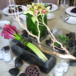Table centerpiece with orchids, calla lilies, and succulents in glass containers