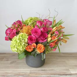 Bright mixed bouquet of pink and orange flowers in a gray vase