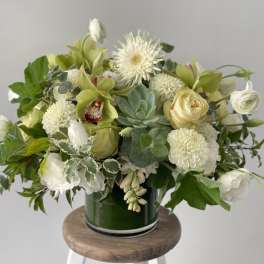 White and pale green floral arrangement in a green glass vase
