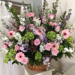 Large basket arrangement of pink roses, gerbera daisies, and purple blooms