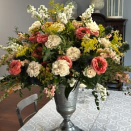 Large mixed floral arrangement in a silver urn on a table