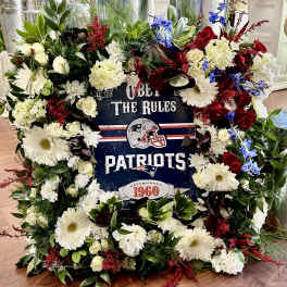 Patriots-themed floral wreath with white, red, and blue flowers around a sign
