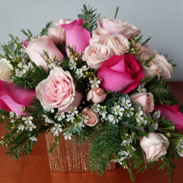 Pink and blush roses arranged in a gold square vase