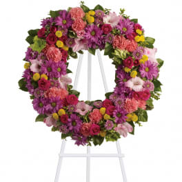 Circular floral wreath on a white easel with pink, purple, and yellow blooms
