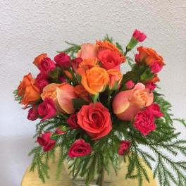 Bouquet of orange and pink roses in a clear glass vase