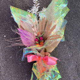 Bouquet with pink and orange dried flowers wrapped in iridescent paper