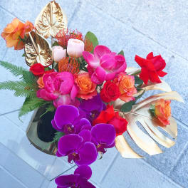 Tropical bouquet with orchids, roses, and gold leaves in a vase