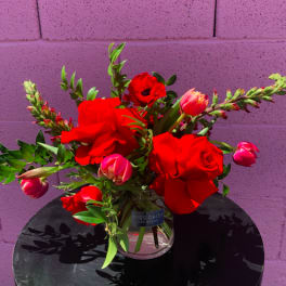 Red roses and pink tulips in a clear glass vase