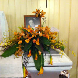 Orange floral arrangement on a white casket with a framed photo
