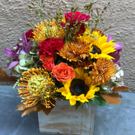 Mixed bouquet with sunflowers, roses, and chrysanthemums in a wooden box