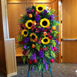 Tall standing floral spray with sunflowers, roses, and purple blooms