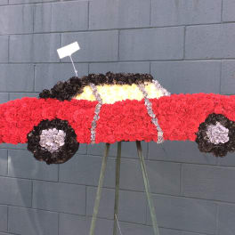 Floral arrangement shaped like a red car on a stand