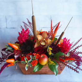 Tropical floral arrangement with red and orange blooms in a wooden container